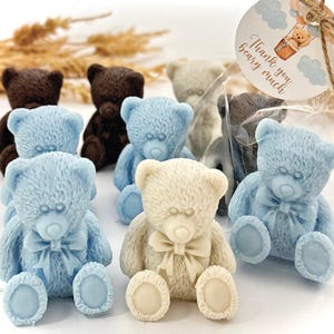 May include: Assortment of small teddy bear shaped soaps in blue, brown, and white. The soaps are packaged in clear cellophane bags with a thank you tag that says "Thank you bear-y much".