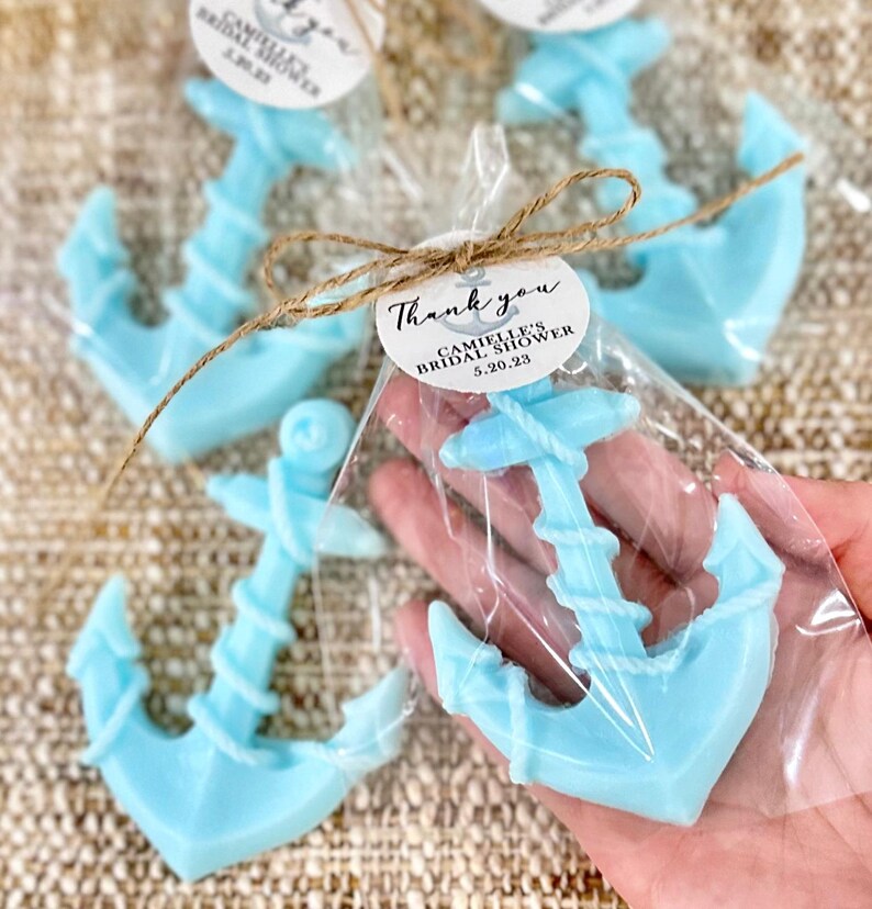 May include: Light blue anchor-shaped soap favors wrapped in clear cellophane bags with a brown twine bow and a round white tag that says "Thank you, Camille's Bridal Shower, 5.20.23"