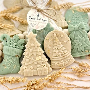 May include: A collection of holiday-themed wax melts in shapes of a stocking, a Christmas tree, a snow globe, and a bell. The items are colored in sage green and cream, with a clear plastic bag tied with twine and a tag reading Happy Holidays FROM THE WALKERS 2026.