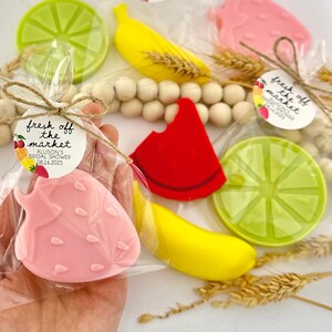 May include: A set of four fruit-shaped soaps wrapped in clear cellophane bags with a small tag that reads "fresh off the market Allison's Bridal Shower 08.16.2025". The soaps are shaped like a strawberry, a banana, a watermelon slice, and a lime.