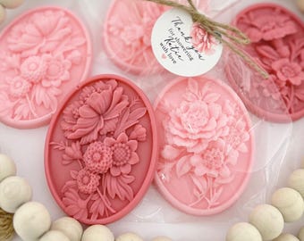 May include: Four oval-shaped pink and red floral soap favors with a thank you tag that reads "Thank you for showering Katie with love".