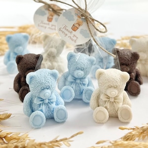 May include: Assortment of small teddy bear shaped favors in blue, white, and brown. The bears are wearing a bow tie and are packaged in clear cellophane bags with a tag that says "Thank you bear-y much".