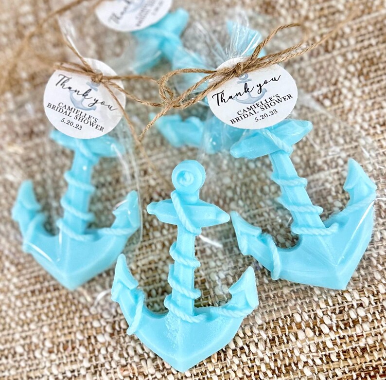 May include: Three blue anchor-shaped favors in clear cellophane bags tied with twine and a round tag that says "Thank you, Camille's Bridal Shower, 5.20.23".