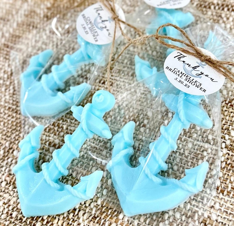 May include: Blue anchor-shaped soap favors with a rope design, packaged in clear cellophane bags with a round thank you tag that reads "Thank you, Camille's Bridal Shower, 5.20.23".