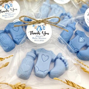 Może przedstawiać: Niebieskie upominki na baby shower w przezroczystym woreczku z celofanu z karteczką z podziękowaniem, na kt&oacute;rej widnieje napis "Dziękujemy Alicia's Baby Shower 09.15.2025". Upominki mają kształt butelki, body i stopy.