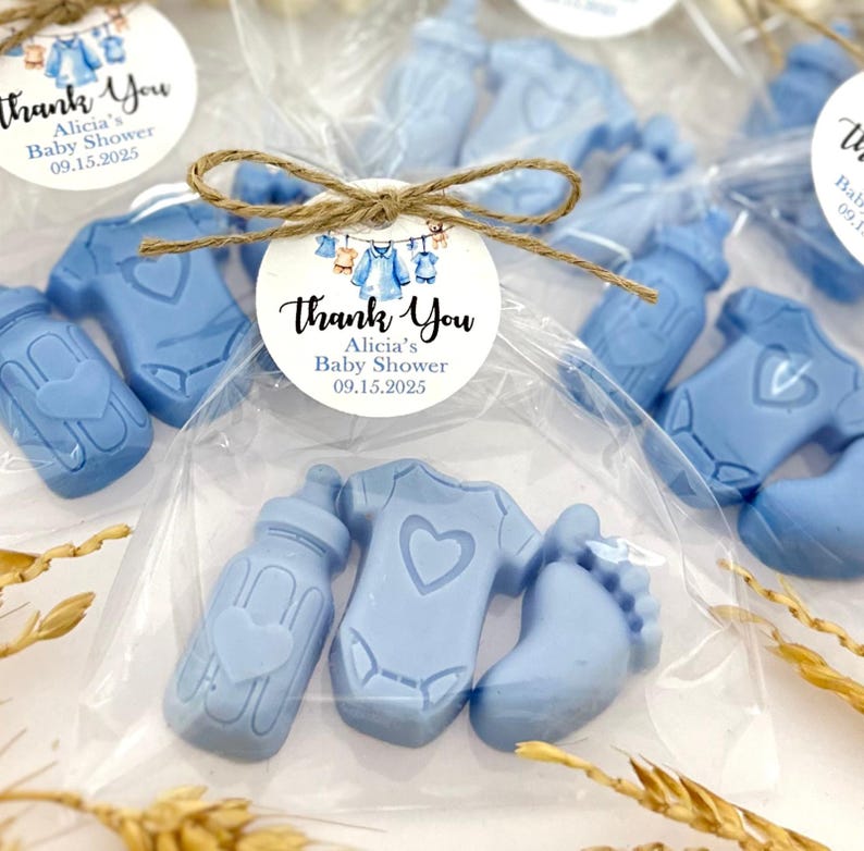 Może przedstawiać: Niebieskie upominki na baby shower w przezroczystym woreczku z celofanu z karteczką z podziękowaniem, na kt&oacute;rej widnieje napis "Dziękujemy Alicia's Baby Shower 09.15.2025". Upominki mają kształt butelki, body i stopy.