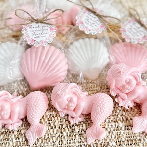 May include: Pink and white seashell shaped soaps with a mermaid shaped soap in a clear bag with a thank you tag that says "Thank you for showering Amelia with love".