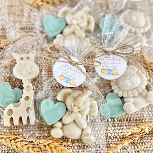 May include: A set of favor bags for a baby shower, each containing a small animal-shaped soap, a heart-shaped soap, and a round tag with the text "Thank you for showering Baby Luca with love!"