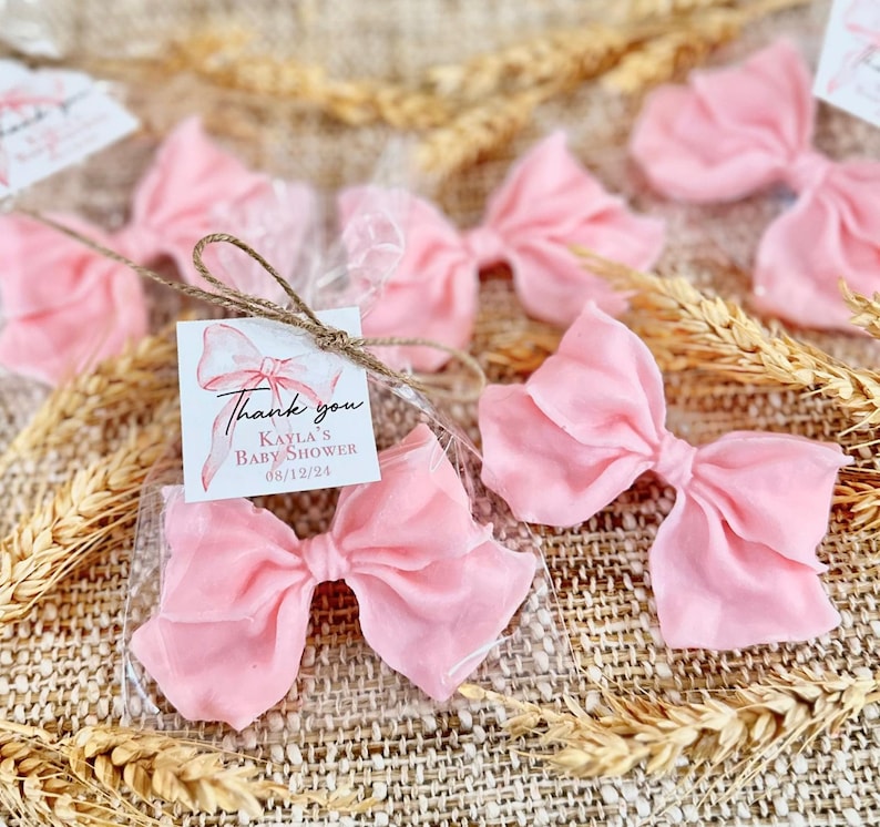 May include: Pink satin bows in clear cellophane bags with a thank you tag that reads "Thank you Kayla's Baby Shower 08/12/24".