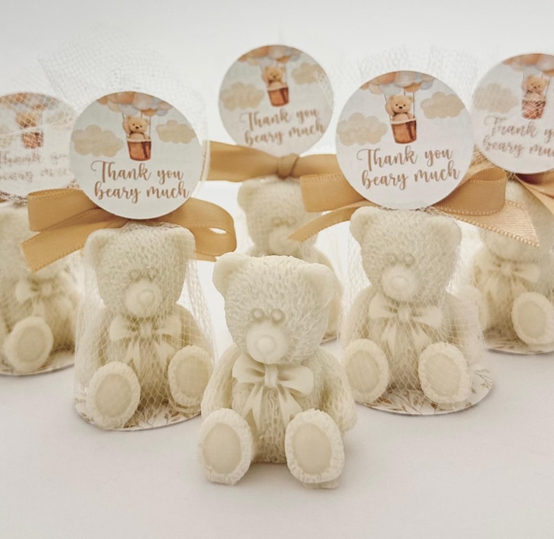 May include: Five small white teddy bear figurines with brown bows are packaged in clear cellophane bags with gold ribbon and a round tag that says "Thank you beary much".