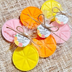May include: Orange, pink, and yellow citrus-shaped soaps wrapped in cellophane bags with a thank you tag that reads "Thank you Olivia's Bridal Shower 08-16-2024".