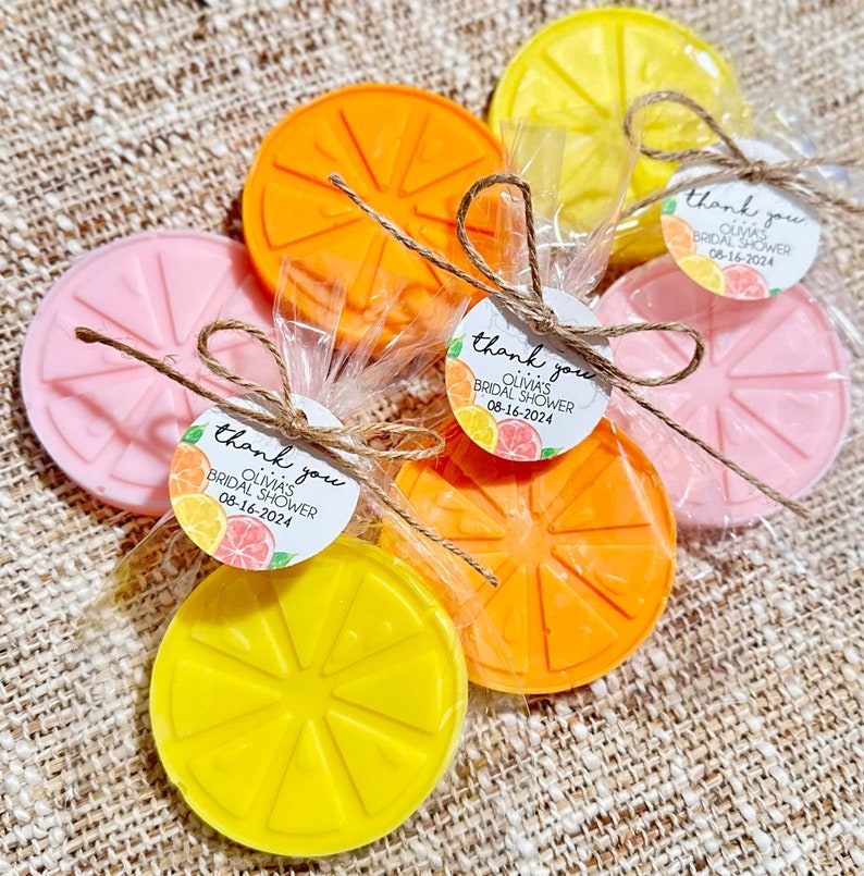May include: Orange, pink, and yellow citrus-shaped soaps wrapped in cellophane bags with a thank you tag that reads "Thank you Olivia's Bridal Shower 08-16-2024".