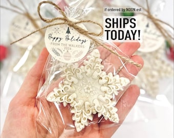 May include: A snowflake-shaped cookie, intricately designed with floral patterns, is packaged in clear cellophane. The cookie is tied with twine and a circular tag that reads "Happy Holidays from the Walkers 2024".