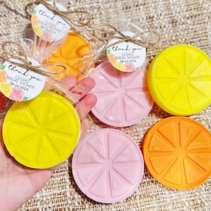 May include: Assortment of six round lemon-shaped soaps in yellow, orange, and pink. Each soap has a raised design of a lemon slice. The soaps are packaged in clear cellophane bags with a small tag that says "Thank you Olivia's Bridal Shower 08-16-2024".