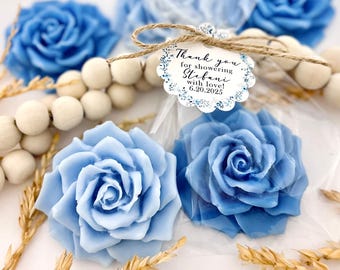 May include: Blue rose-shaped soaps, some wrapped in clear cellophane, are arranged with wooden beads and dried wheat. A tag reads "Thank you for showering Stefani with love! 6.20.2025."