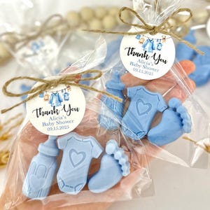 Może przedstawiać: Niebieskie torebki na prezenty z okazji baby shower z etykietą z podziękowaniem, na kt&oacute;rej widnieje napis "Dziękujemy Alicia's Baby Shower 09.15.2025". Torebki zawierają niebieskie mydło w kształcie butelki, body i stopy.