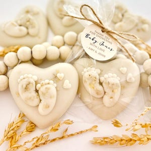 May include: Heart-shaped favors with baby footprints, wheat stalks, and wooden beads. Some favors are packaged in clear cellophane bags with a tag that reads "Thank you for showering Baby Jones with love - Amy & John."