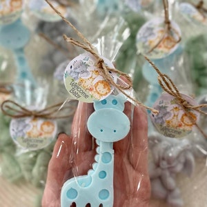 Puede incluir: Favores de jab&oacute;n en forma de jirafa azul claro envueltos en bolsas de celof&aacute;n transparentes con un lazo de cuerda marr&oacute;n y una etiqueta redonda que dice "Bienvenido Beb&eacute;" con un dise&ntilde;o de animales de la selva.