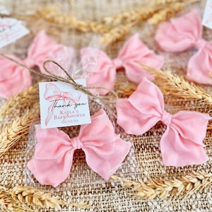 May include: Pink satin bows tied with twine and packaged in clear cellophane bags. Each bag includes a small thank you tag with the text "Thank you Kayla's Baby Shower 08/12/24".