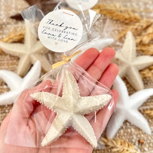 May include: A white starfish in a clear plastic bag with a thank you tag that reads "Thank you for celebrating Emma & Liam with love".