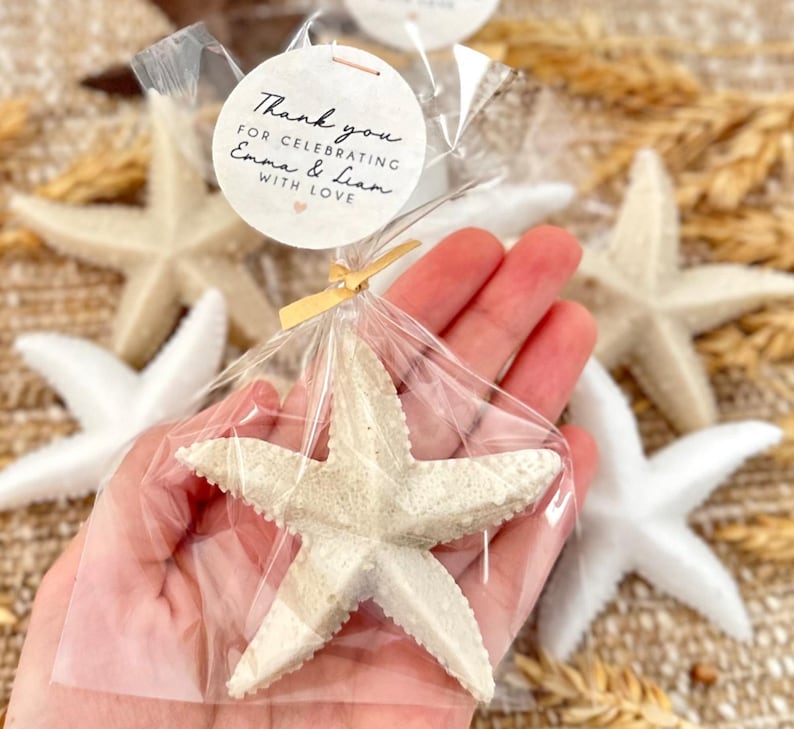 May include: A white starfish in a clear plastic bag with a thank you tag that reads "Thank you for celebrating Emma & Liam with love".