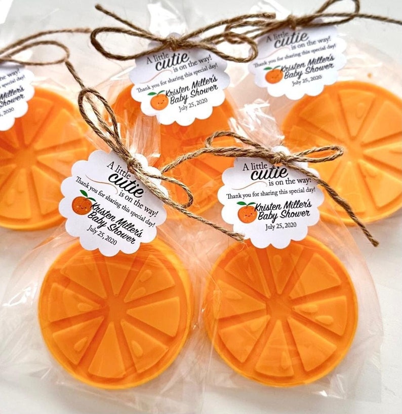 May include: Orange-scented soap favors with a white tag that reads "A little cutie is on the way! Thank you for sharing this special day! Kristen Miller's Baby Shower July 25, 2020"