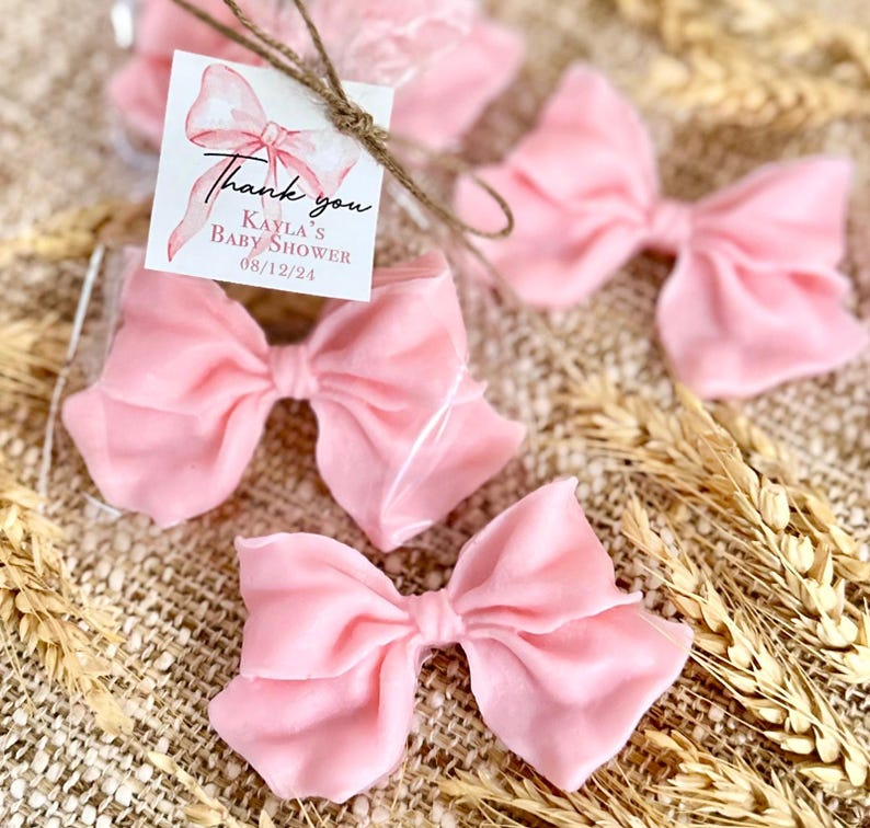 May include: Pink satin bows with a thank you tag that reads "Thank you Kayla's Baby Shower 08/12/24".