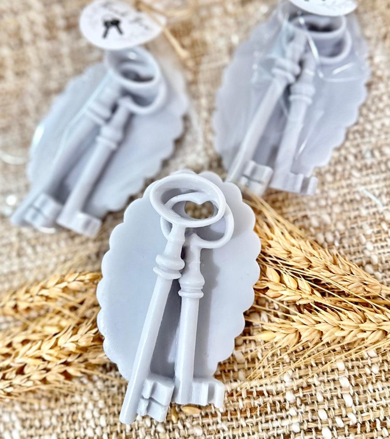 May include: Two sets of antique-style keys in a light gray oval frame. The keys are made of a smooth, light gray material and have intricate details. The frames are decorated with a scalloped edge.