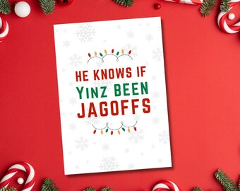 以下が含まれることがあります： 赤、緑、黄色のクリスマスライトのガーランドデザインが施された白いカード。カードには「He knows if Yinz been Jagoffs」という黒いテキストが書かれています。
