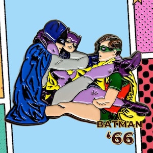 Może przedstawiać: Emaliowana przypinka z Batmanem, Catwoman i Robinem z serialu telewizyjnego z 1966 roku. Przypinka przedstawia postacie w dynamicznej pozie, z żywymi kolorami, w tym niebieskim, fioletowym, żółtym i zielonym. Tekst "BATMAN '66" jest wyświetlany na dole.