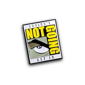 Op de afbeelding: Een gele en zwarte emaille pin met de tekst "Couldn't Not Going Get In" en een cartoonoog met een opgeheven wenkbrauw.