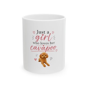 May include: White ceramic mug with the text "Just a girl who loves her cavapoo" in pink and black. A cartoon image of a brown Cavapoo dog is below the text, with pink hearts and a black heart.