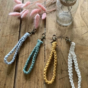 Puede incluir: Cuatro llaveros de macramé hechos a mano en diferentes colores: azul claro, verde azulado, amarillo y blanco. Los llaveros están hechos con un cordón grueso y trenzado y tienen un diseño simple y minimalista.