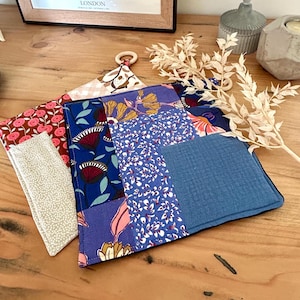 Peut inclure: Ensemble de dessous de plats patchwork aux motifs floraux et colorés. Les couleurs incluent le bleu, le rose et le jaune. L'un d'eux est équipé d'un anneau en bois pour être suspendu.
