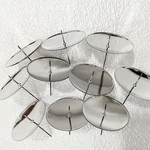 May include: A collection of silver-colored metal candle holders. Each holder features a circular base with a central spike, connected to a thin, black stem. The arrangement suggests a decorative or artistic display, suitable for home decor.