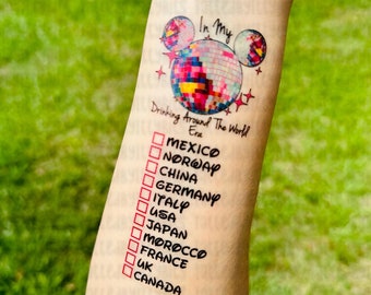Op de afbeelding: Een tijdelijke tattoo met een kleurrijk Mickey Mouse-hoofdontwerp en de tekst "In My Drinking Around The World Era". Onder het ontwerp staat een lijst met landen met vinkjes ernaast: Mexico, Noorwegen, China, Duitsland, Italië, VS, Japan, Marokko, Frankrijk, VK, Canada.
