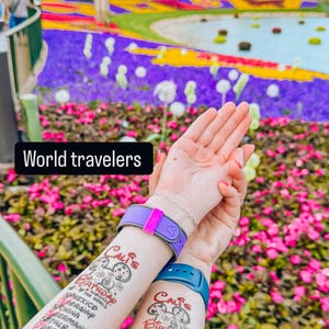 May include: Two people's arms with temporary tattoos that list countries they have visited. The tattoos say "Cali's Birthday" and list countries like Norway, Mexico, China, Germany, Italy, USA, Japan, Morocco, France, and Canada. The tattoos are on their forearms and they are holding their hands up in front of a colorful flower bed.