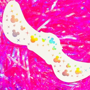 Könnte beinhalten: Ein weißer, geschwungener Aufkleber mit holografischen Mickey Mouse Kopf- und Stern-Designs. Der Aufkleber hat ein farbenfrohes, glitzerndes Aussehen vor einem leuchtend pinkfarbenen, strukturierten Hintergrund.