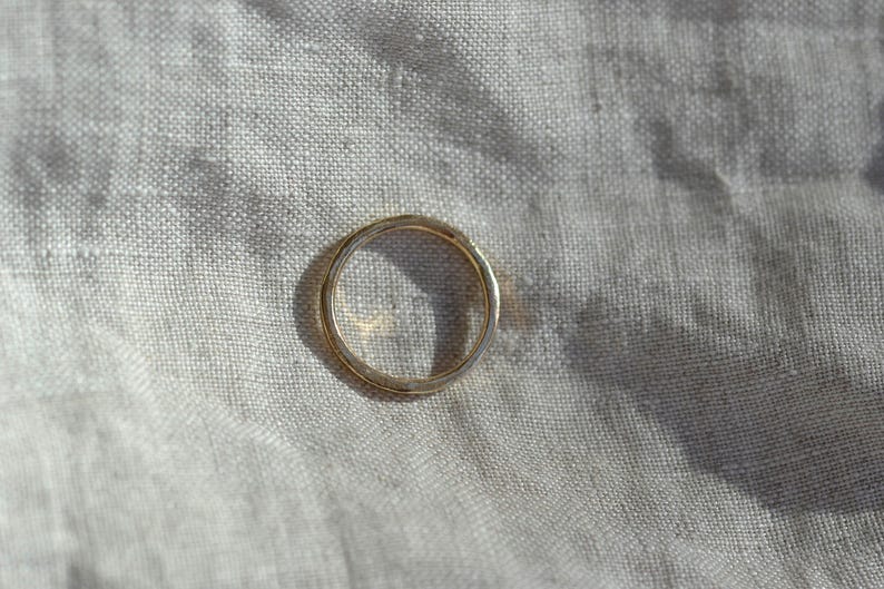 Puede incluir: Un anillo de banda de oro circular simple con un acabado liso y pulido. El anillo presenta un perfil redondeado y consistente en toda su circunferencia, mostrando un tono amarillo met&aacute;lico c&aacute;lido que refleja la luz en su superficie.