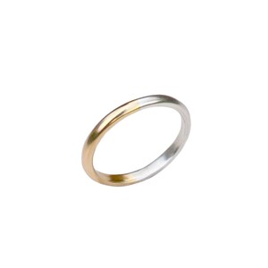 May include: A simple gold and silver wedding band. The band is made of two metals, with the gold on the outside and the silver on the inside.