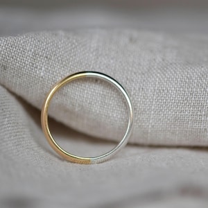 May include: A simple silver and gold band ring. The ring is half silver and half gold.