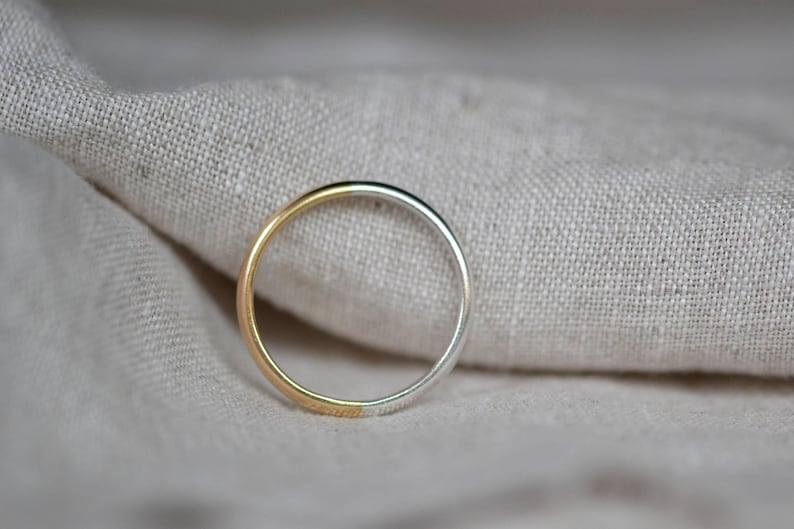 May include: A simple silver and gold band ring. The ring is half silver and half gold.
