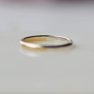 May include: A simple gold and silver band ring. The ring is half gold and half silver.