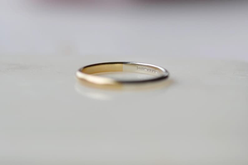 May include: A simple gold and silver band ring. The ring is half gold and half silver.