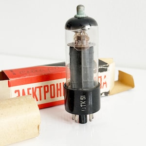 May include: A vintage vacuum tube with a clear glass bulb and a black base. The tube has internal components visible through the glass and is labelled "OTK51". The tube is displayed with its original packaging, which features red and white text.