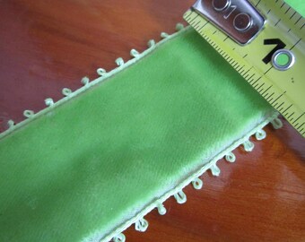 May include: A lime green velvet ribbon with a white crocheted edge. The ribbon is measured with a tape measure, showing 10 inches.