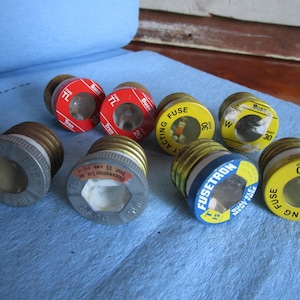 Può includere: Assortimento di otto cartucce di fusibili in vetro con diversi valori di amperaggio. I fusibili sono etichettati con i marchi Buss, Fusetron e Fast Acting. I fusibili sono di vari colori, tra cui rosso, giallo e blu.