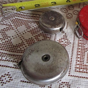 Vintage metal spool measuring tape in distressed condition. 1940s vintage tools.