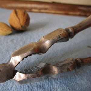 Metal nutcracker tool. Vintage early 20th century silver tone almond or walnut size shucking device. Strong easy grip handle.