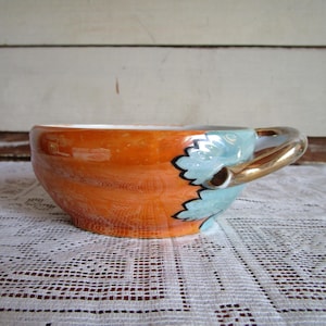 Orange oval condiment, sauce dish w gold tone handle. Lusterware, Japan pre WWII. Cup with leaf design. Hand painted metallic finish.
